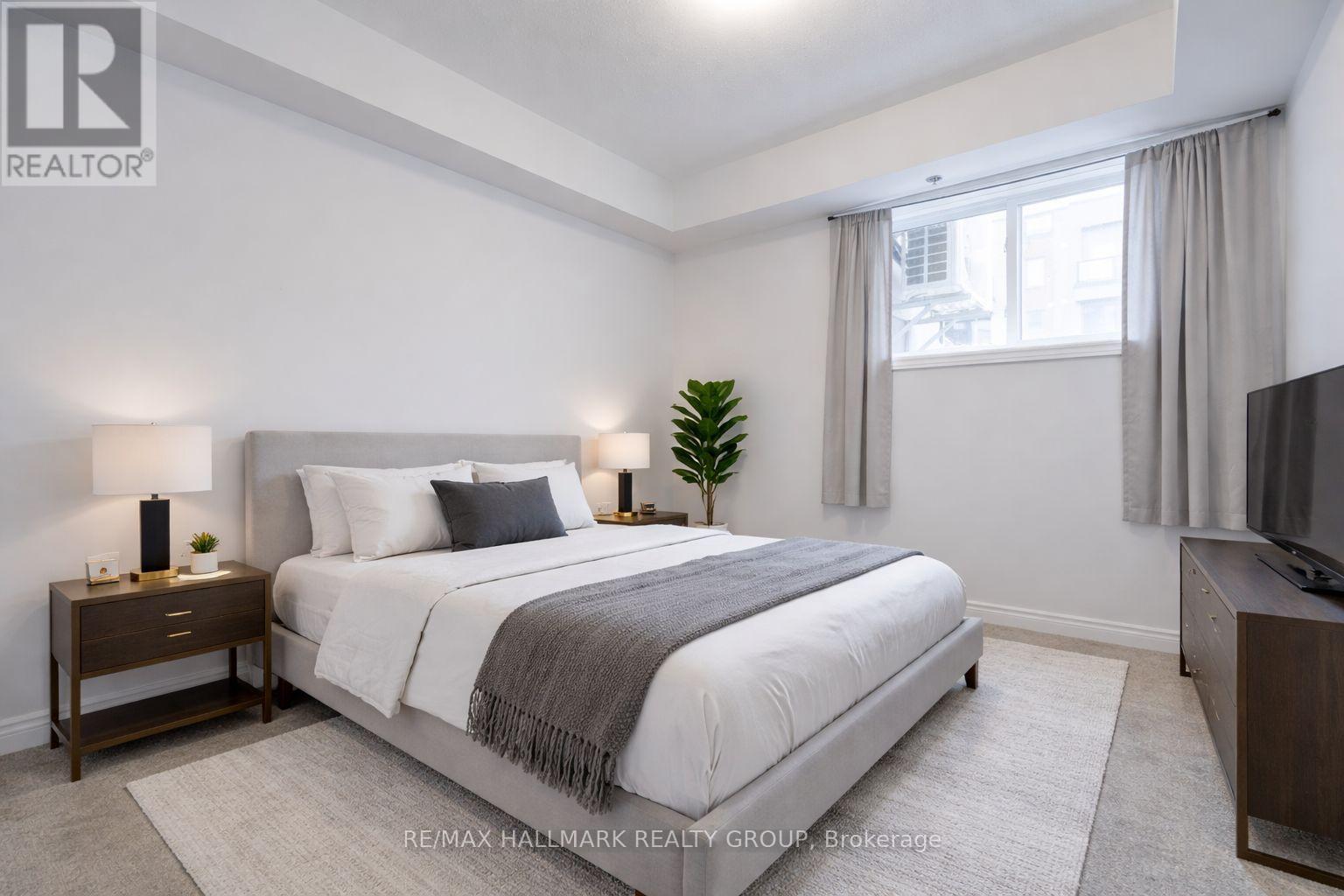 A bedroom with a bed, nightstand, and window.