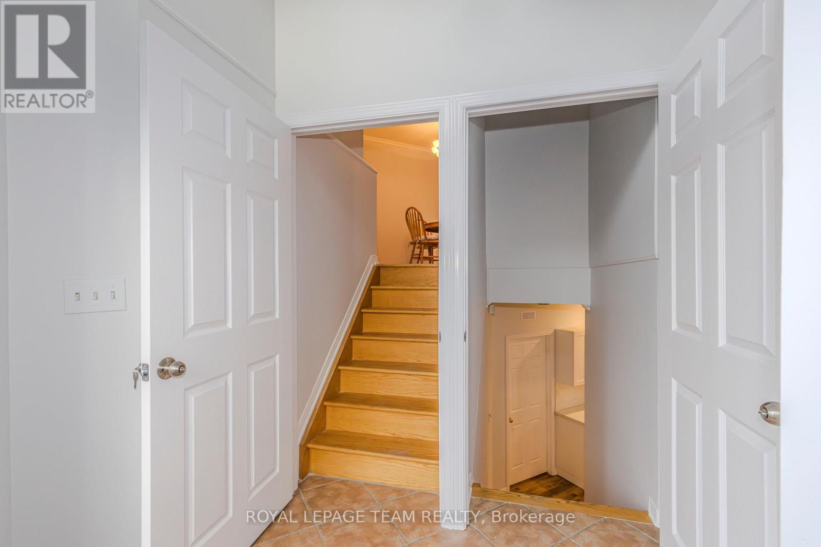 A white doorway opens to a hallway with a staircase.