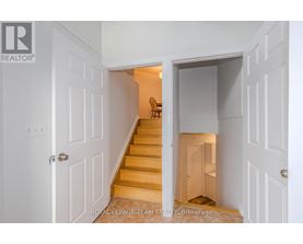 A white doorway opens to a hallway with a staircase.