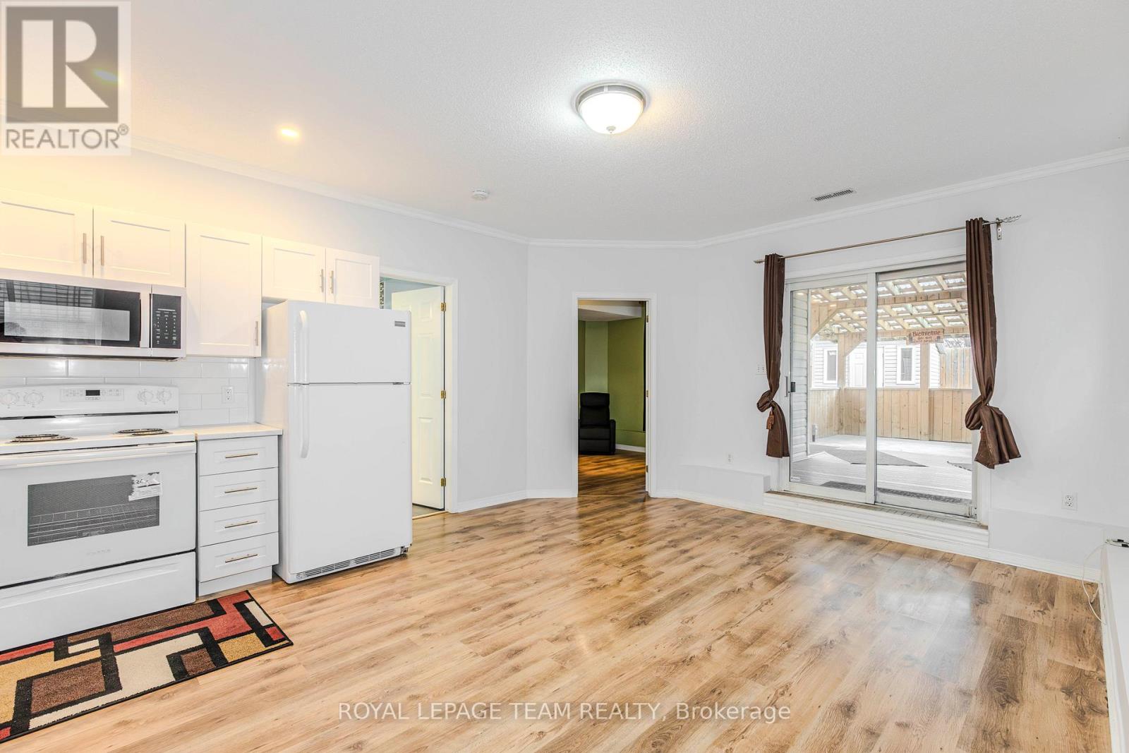 A well-lit, spacious kitchen with white appliances and wooden flooring.
