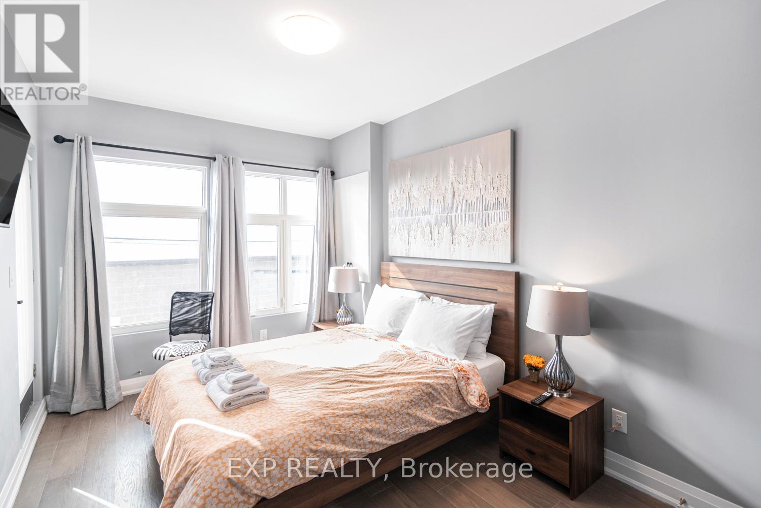 A bedroom with a large bed, a nightstand with a lamp, and a painting on the wall.