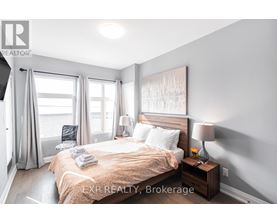 A bedroom with a large bed, a nightstand with a lamp, and a painting on the wall.