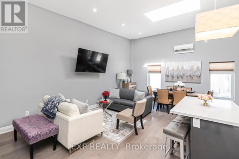A living room with a white couch and a flat screen TV mounted on the wall.