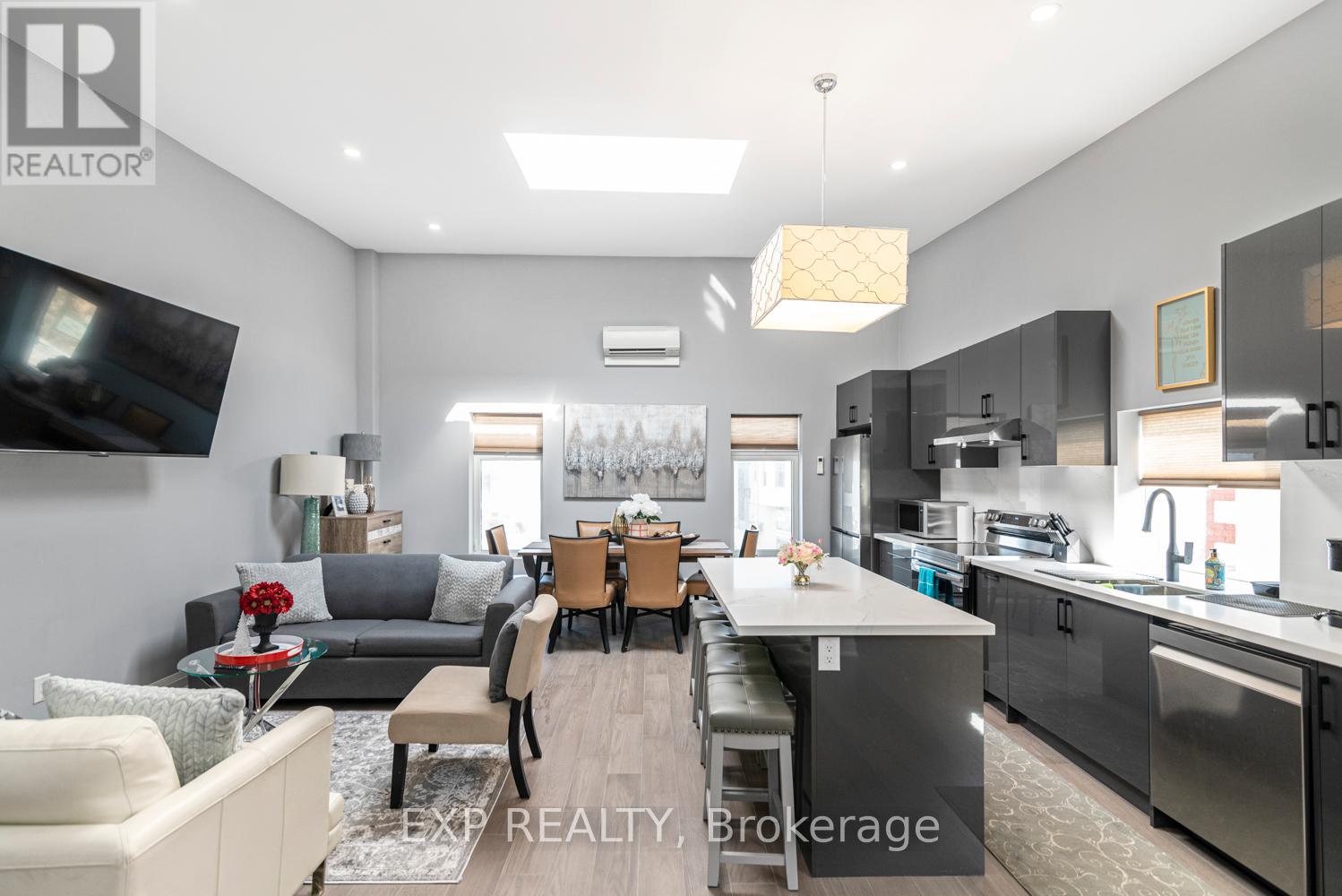 A modern kitchen and living room with a dining area in the middle.