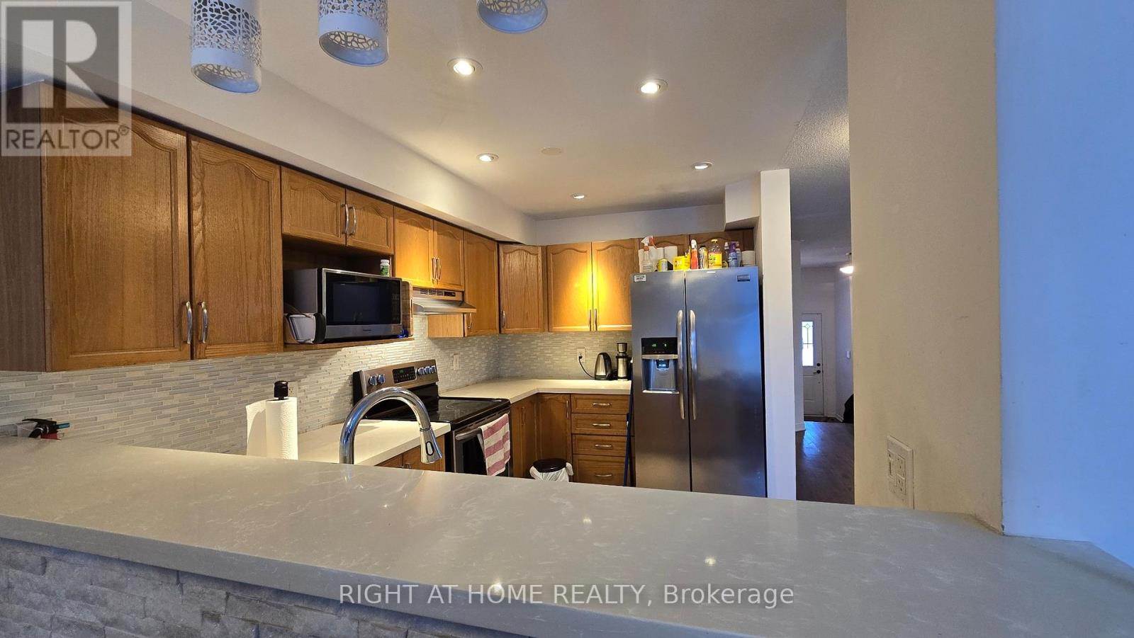 A kitchen with wooden cabinets and a stainless steel refrigerator.