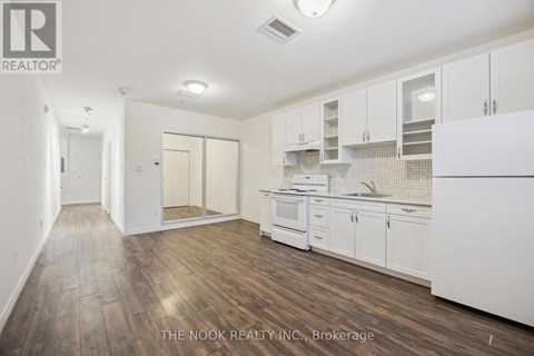 A kitchen with white cabinets and a wooden floor.