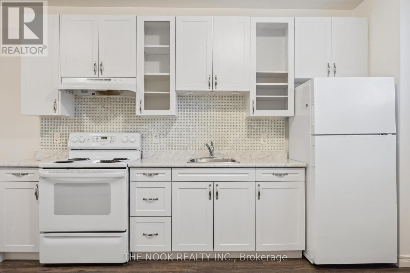 A white kitchen with a refrigerator, stove, and cabinets.