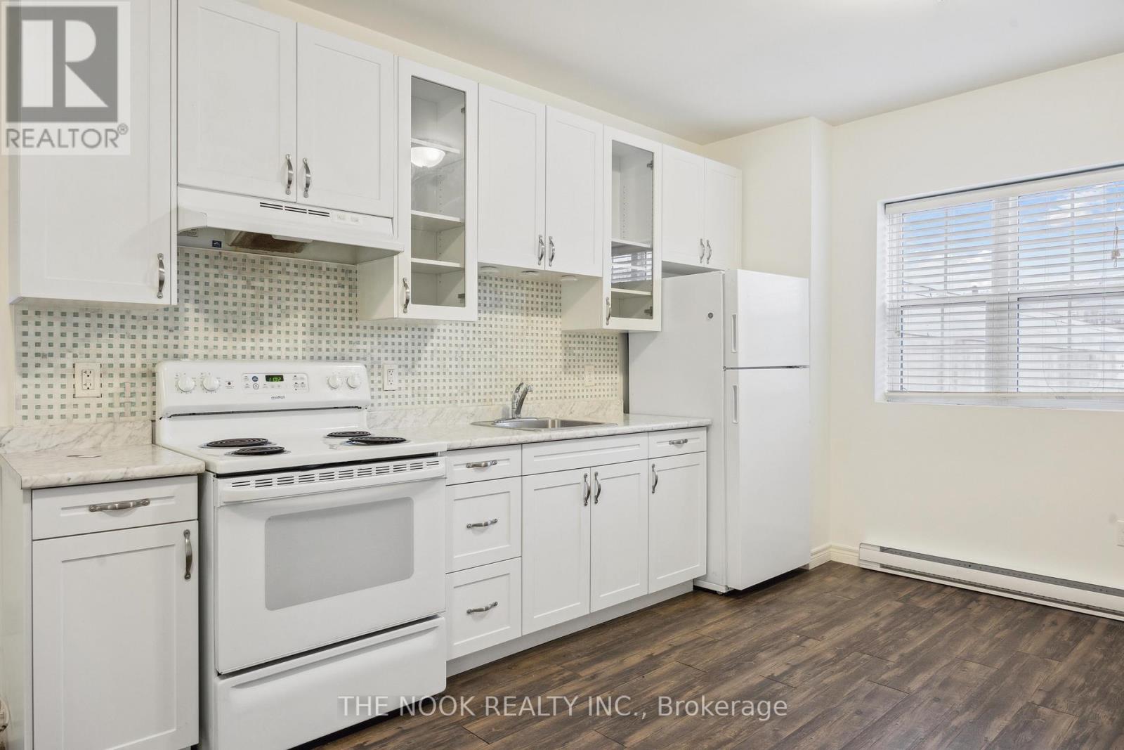 A white kitchen with a stove top oven and a refrigerator.