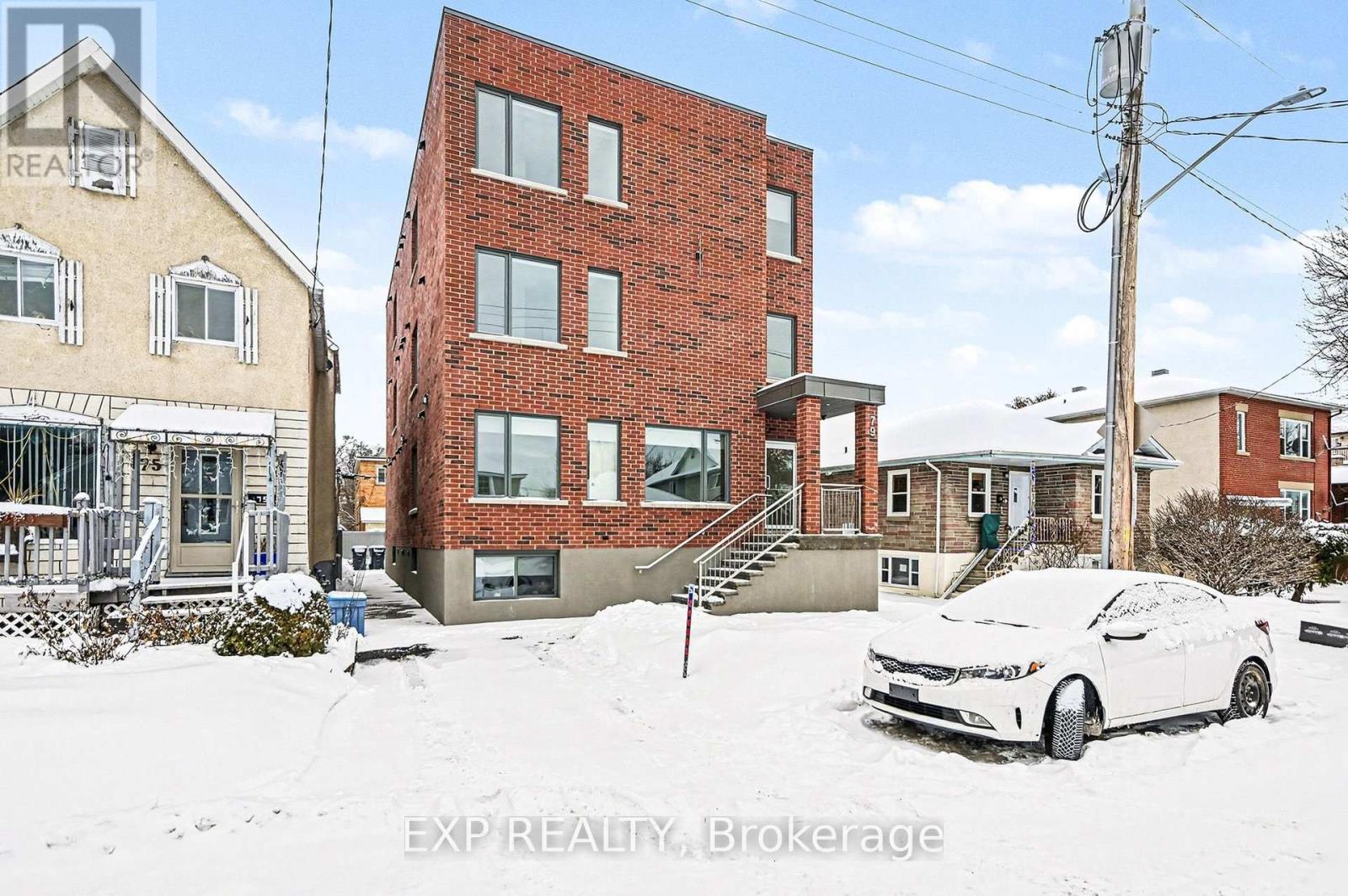 A white car is parked in front of a red brick building.