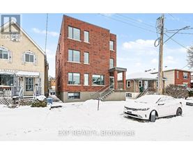 A white car is parked in front of a red brick building.