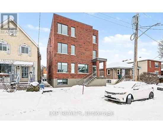 A white car is parked in front of a red brick building.