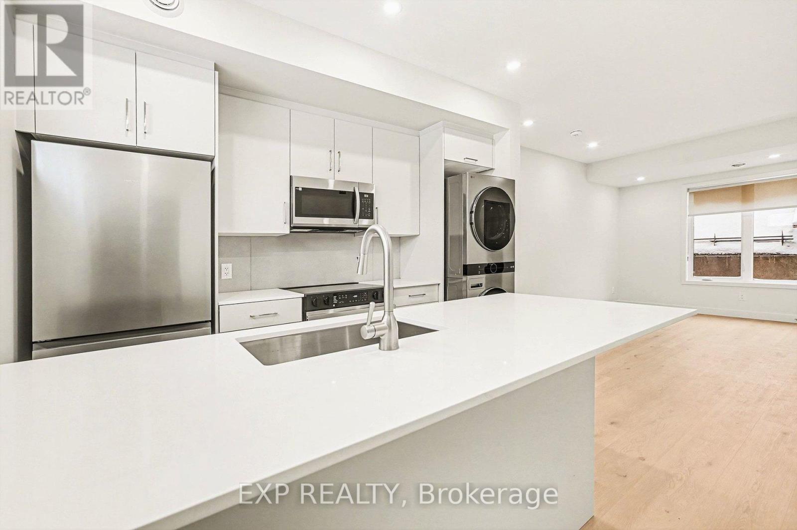 A modern kitchen with white countertops and stainless steel appliances.