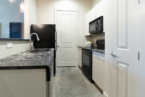 A kitchen with black and white appliances and cabinets.