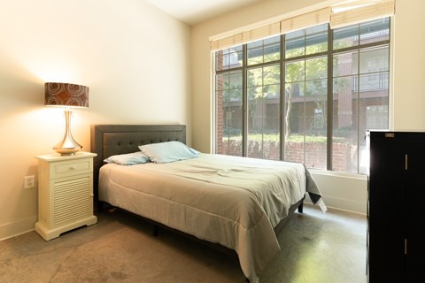 A bedroom with a bed, nightstand, and window.