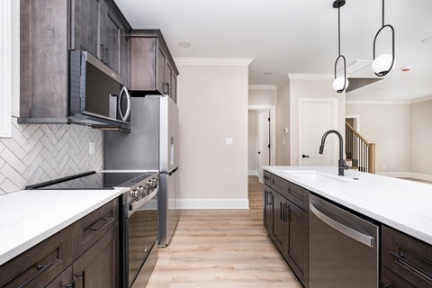 A kitchen with dark wood cabinets and white countertops.