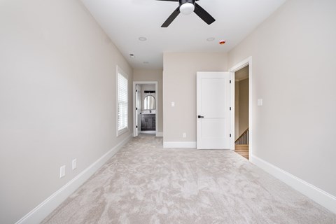 A spacious room with a carpeted floor and a ceiling fan.