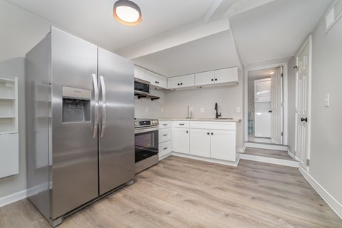 A modern kitchen with a stainless steel refrigerator and white cabinets.