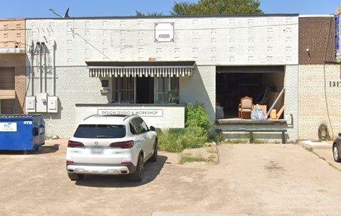A white car is parked in front of a building with a sign that says "Design Studio a Workshop".