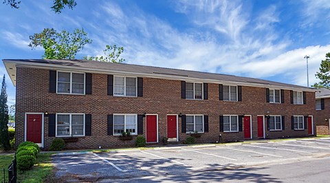 A long brick building with red doors and windows.