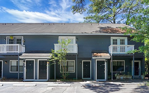A grey two-story house with a balcony on the second floor.