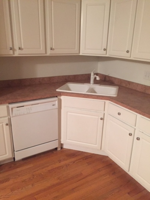 A white dishwasher is in a kitchen with wooden floors.