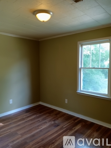 A room with a window and wooden floors.