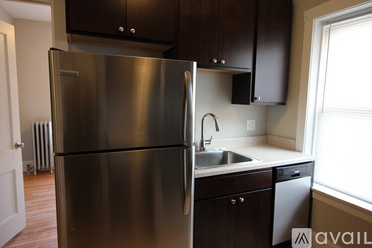 A kitchen with a stainless steel refrigerator and dark brown cabinets.