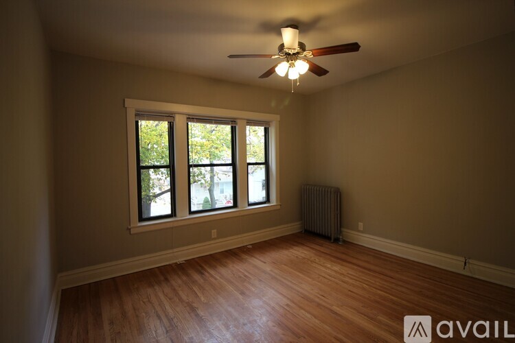 A room with a ceiling fan and a window with a view of trees.