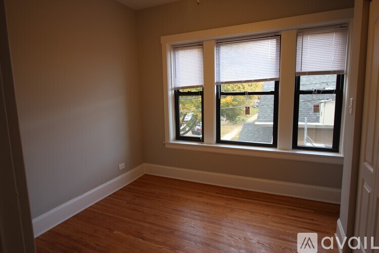 A room with wooden floors and two windows with blinds.