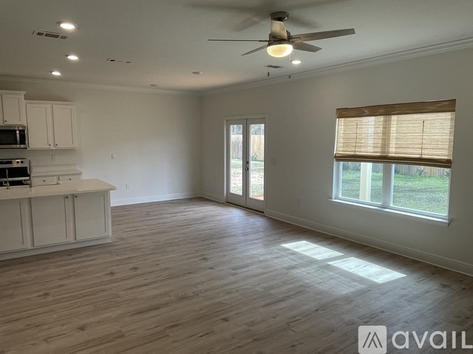 A spacious room with a ceiling fan and wooden flooring.