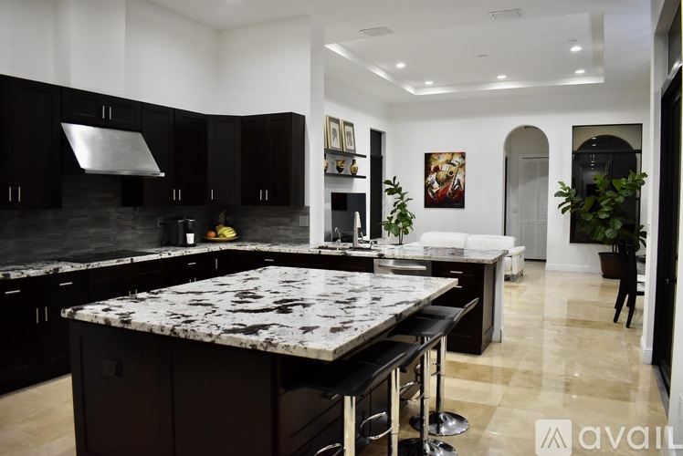 A kitchen with black cabinets and a marble island.