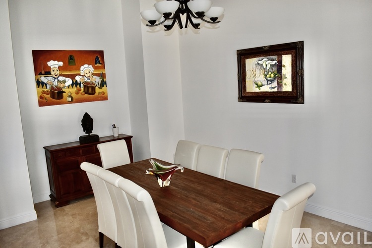 A dining room with a wooden table and white chairs.