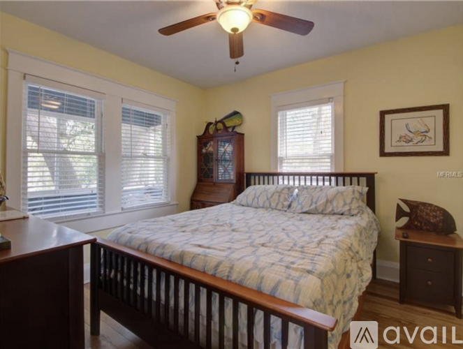A bedroom with a bed, nightstand, and window with blinds.