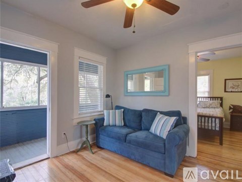 A living room with a blue couch and a ceiling fan.