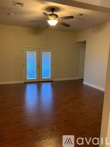 A room with a ceiling fan and wooden flooring.
