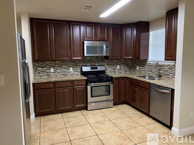 A kitchen with brown cabinets and a granite countertop.