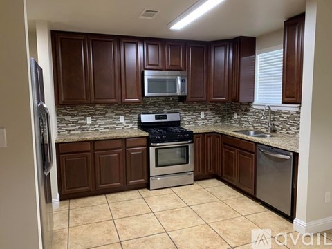 A kitchen with brown cabinets and a granite countertop.
