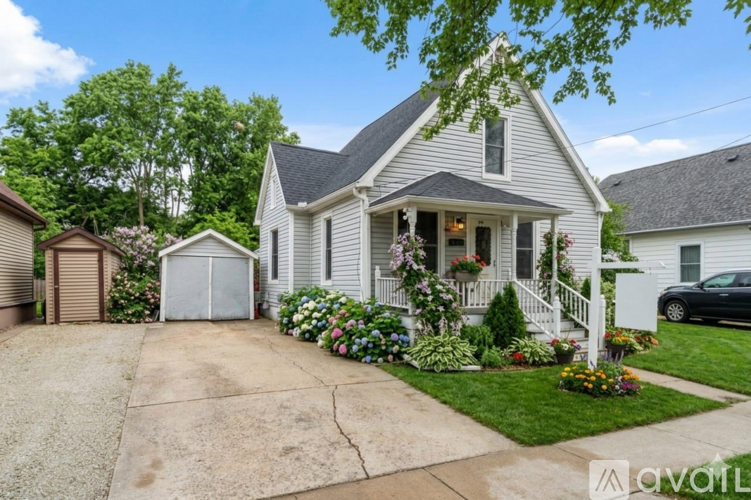 A house with a grey siding and a brown roof is for sale.