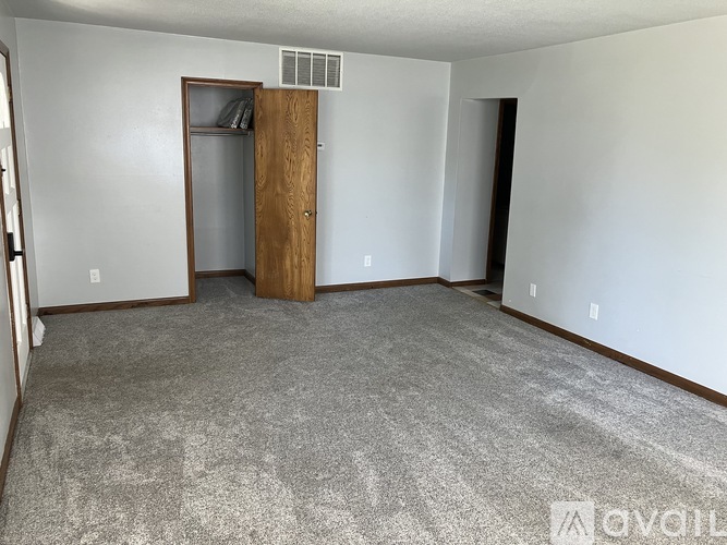 A room with a carpeted floor and a wooden door.