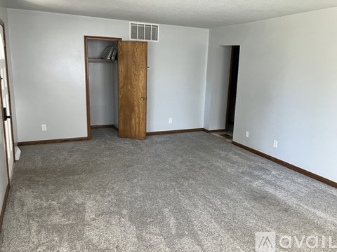 A room with a carpeted floor and a wooden door.