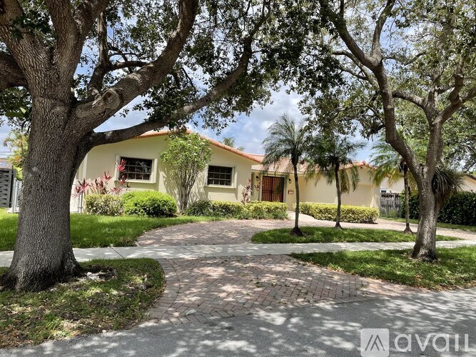A house with a driveway and trees in front.
