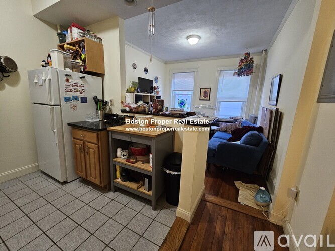 A kitchen with a refrigerator, sink, and a dining table with chairs.