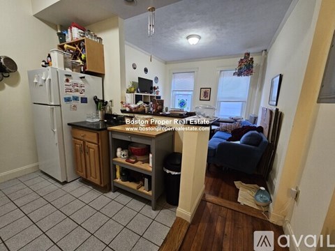 A kitchen with a refrigerator, sink, and a dining table with chairs.
