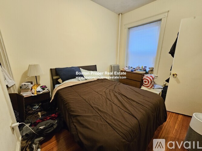 A bedroom with a bed, nightstand, and window.