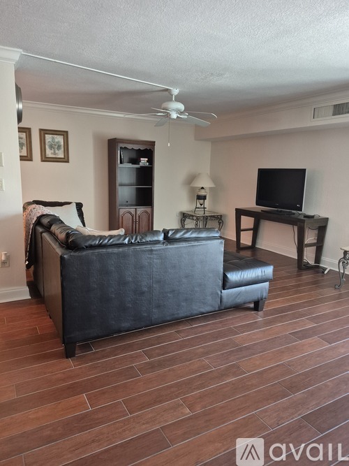 A living room with a black couch and a television on a stand.