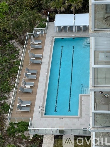 A pool surrounded by lounge chairs and a white building.