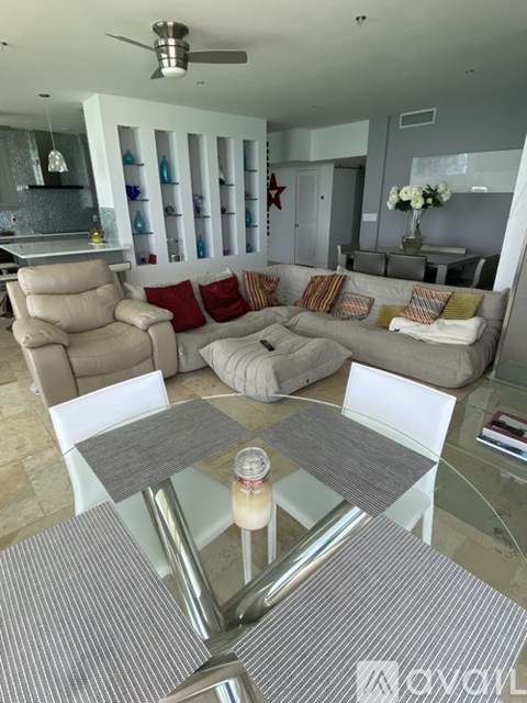 A living room with a glass table and a white chair.