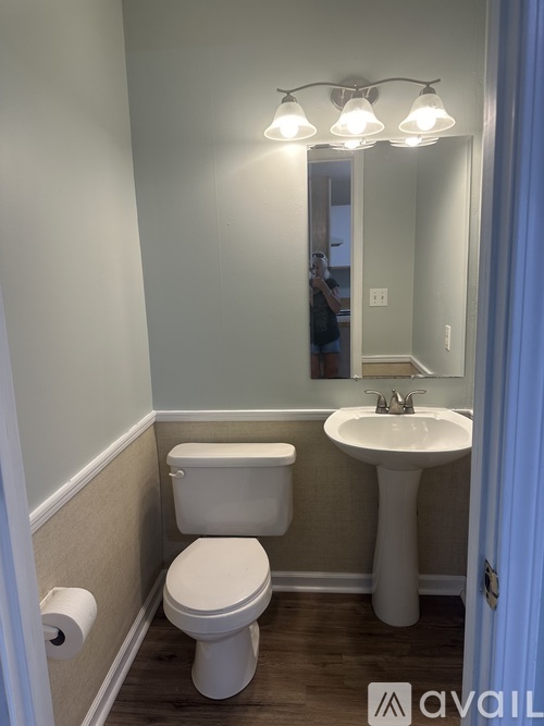 A bathroom with a toilet, sink, and mirror.