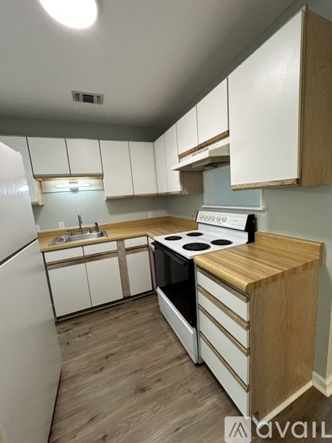 A kitchen with white cabinets and a wooden countertop.