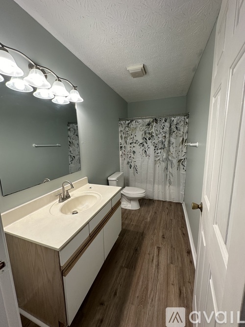 A bathroom with a white sink and a wooden vanity.